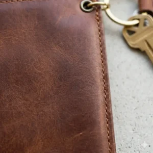 Close-up of the durable stitching and full-grain texture on a leather wallet with keyring.