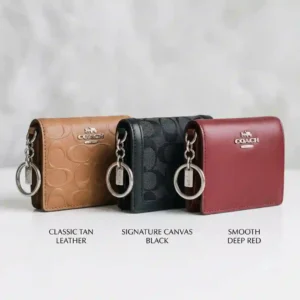 A Coach wallet key ring placed next to a smartphone for size comparison.